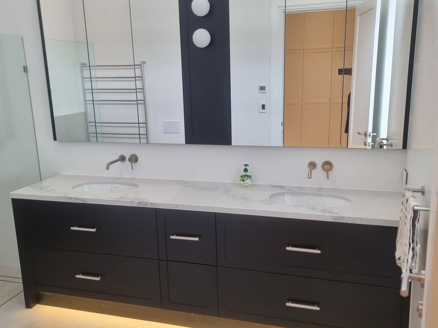Black double vanity with twin basins and wall-hung cabinetry in a renovated bathroom