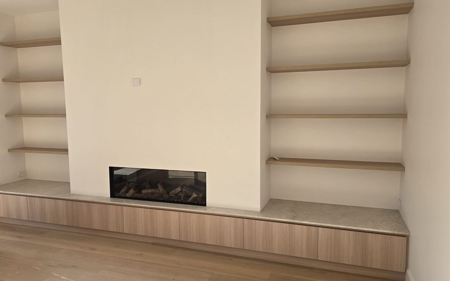 Arched built-in shelving and custom cabinetry surrounding a fireplace