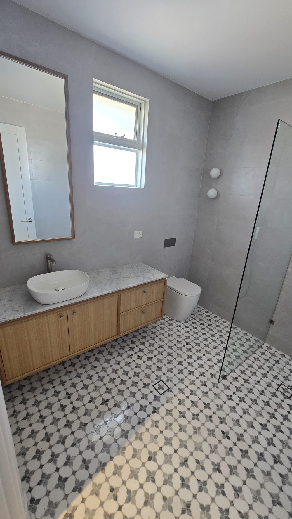 Bathroom with patterned tiles, a freestanding bath, and a window
