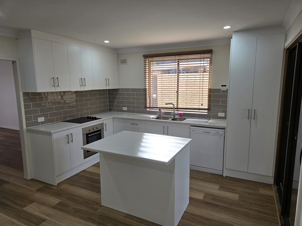 White custom kitchen with an island bench and window
