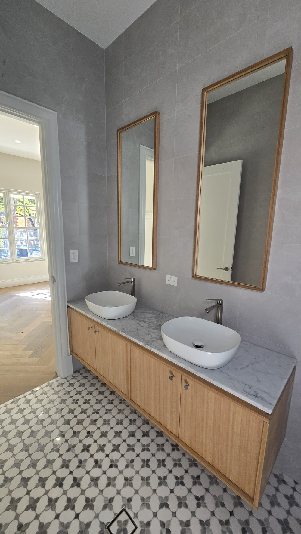 Bathroom with patterned floor tiles and a timber vanity