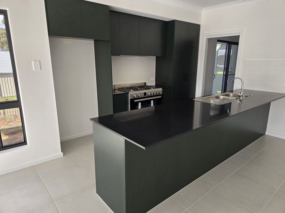 Deep green kitchen with black benchtop, alternate angle