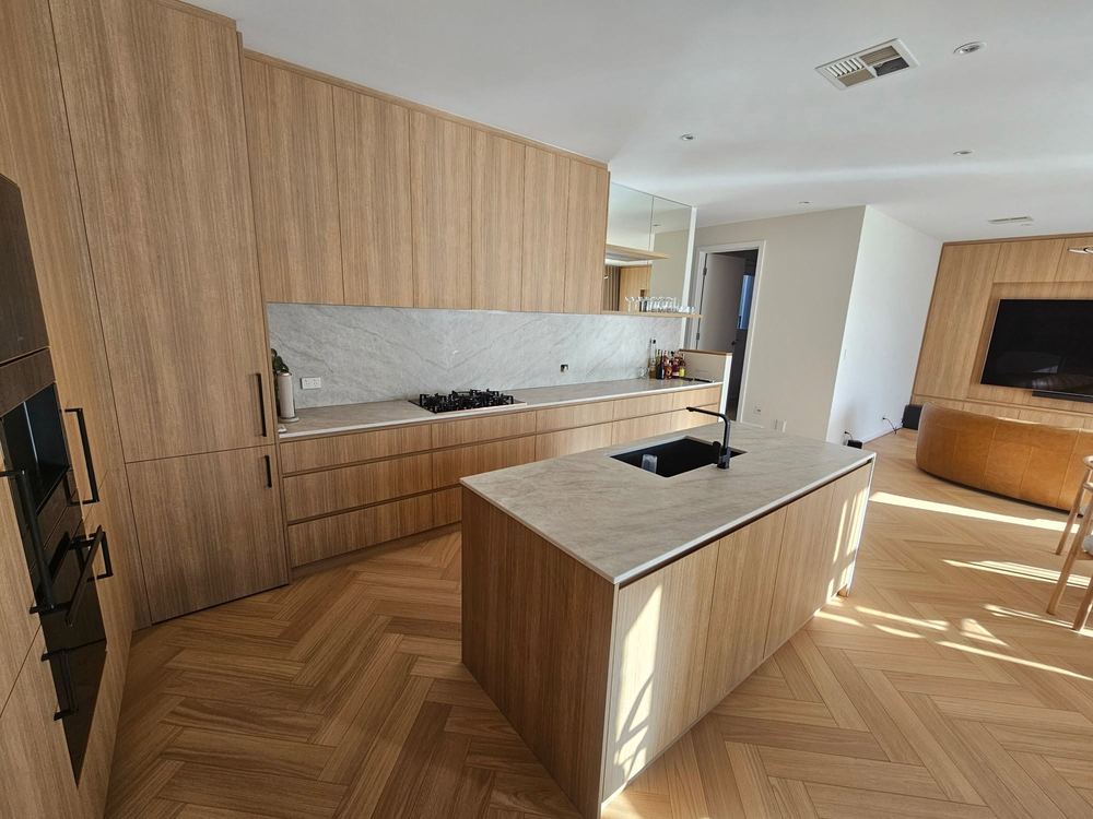 Custom timber kitchen with a stone waterfall island bench and herringbone timber floors