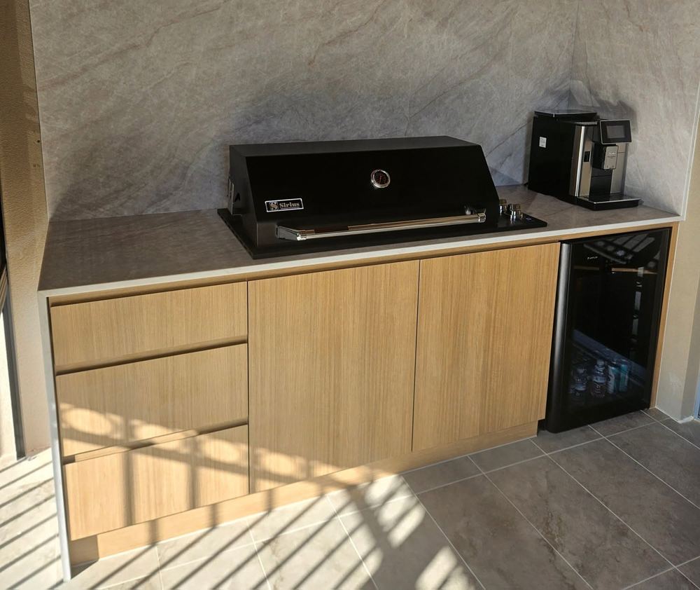 Outdoor alfresco kitchen with timber cabinetry, a stone benchtop, and a built-in barbecue