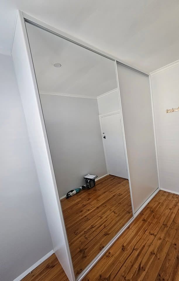 White sliding mirror wardrobe fitted neatly under a raked ceiling