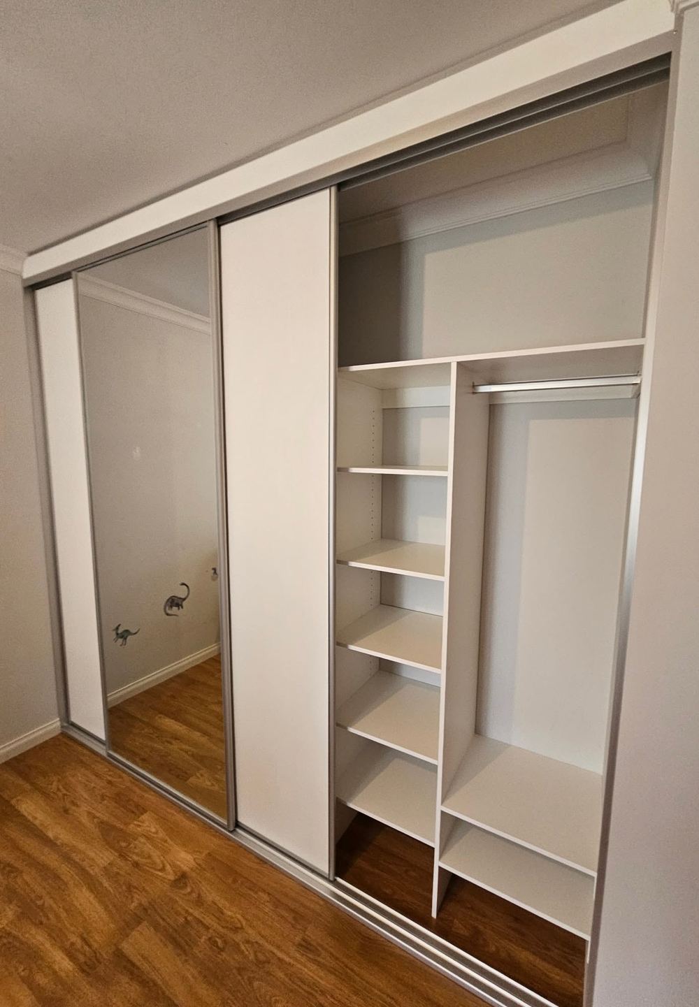 White sliding wardrobe with a hanging rail and open internal shelving
