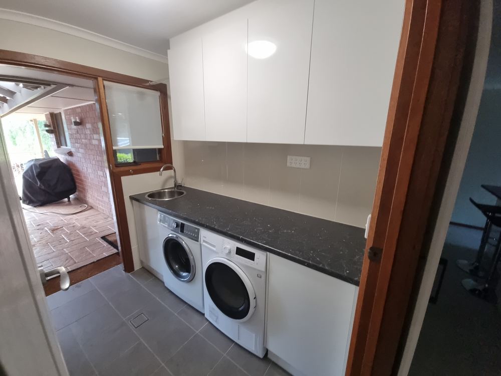 Custom laundry cabinetry with bench space over appliances