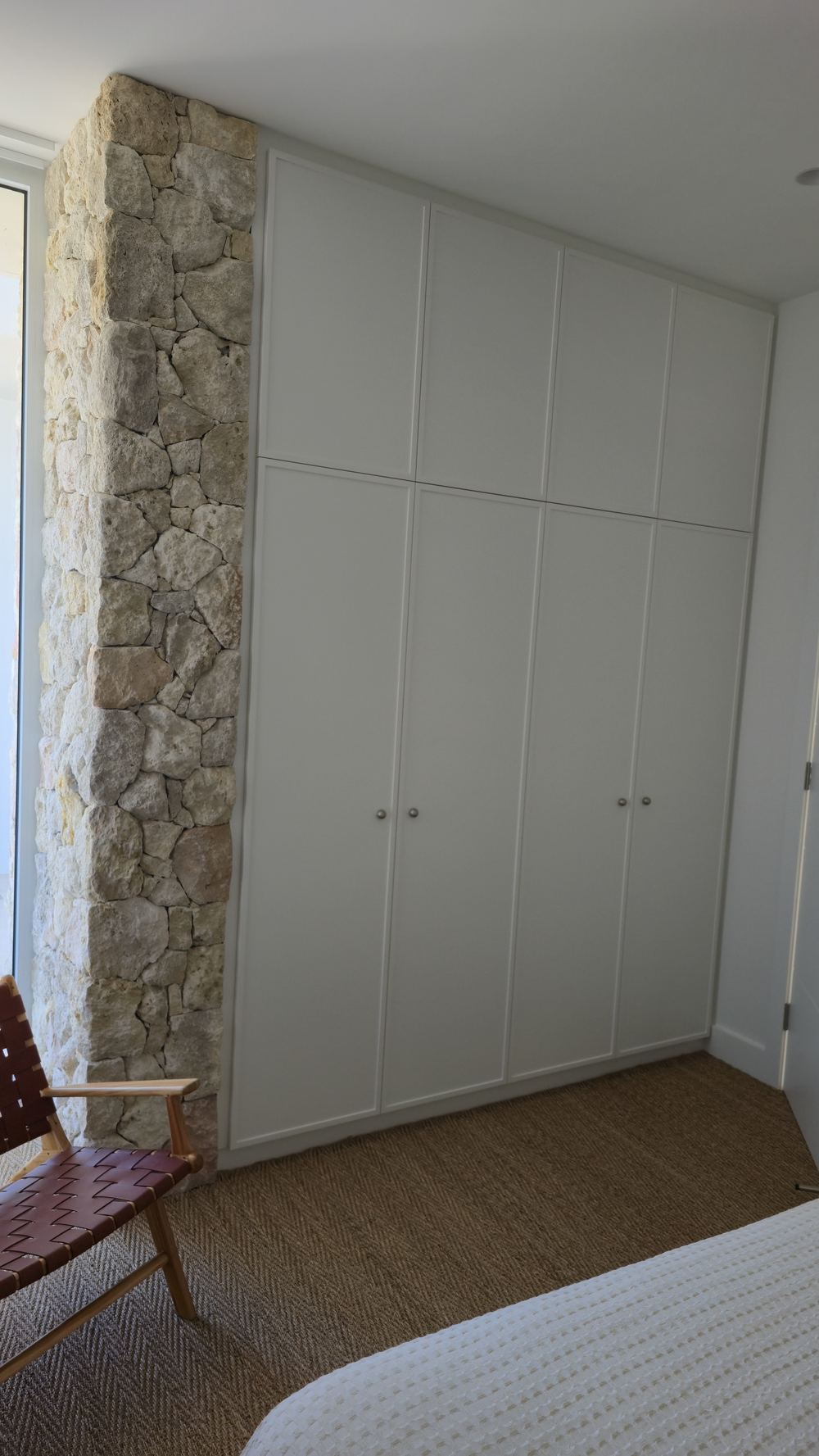 Attic bedroom with custom window seat and storage against a stone feature wall