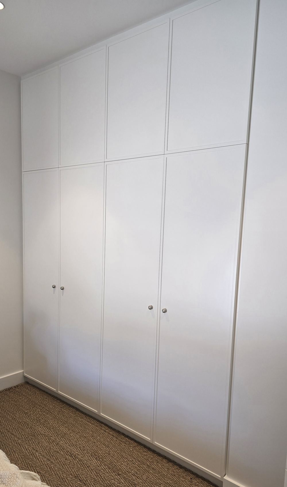 Floor-to-ceiling white built-in wardrobe with handle-free doors