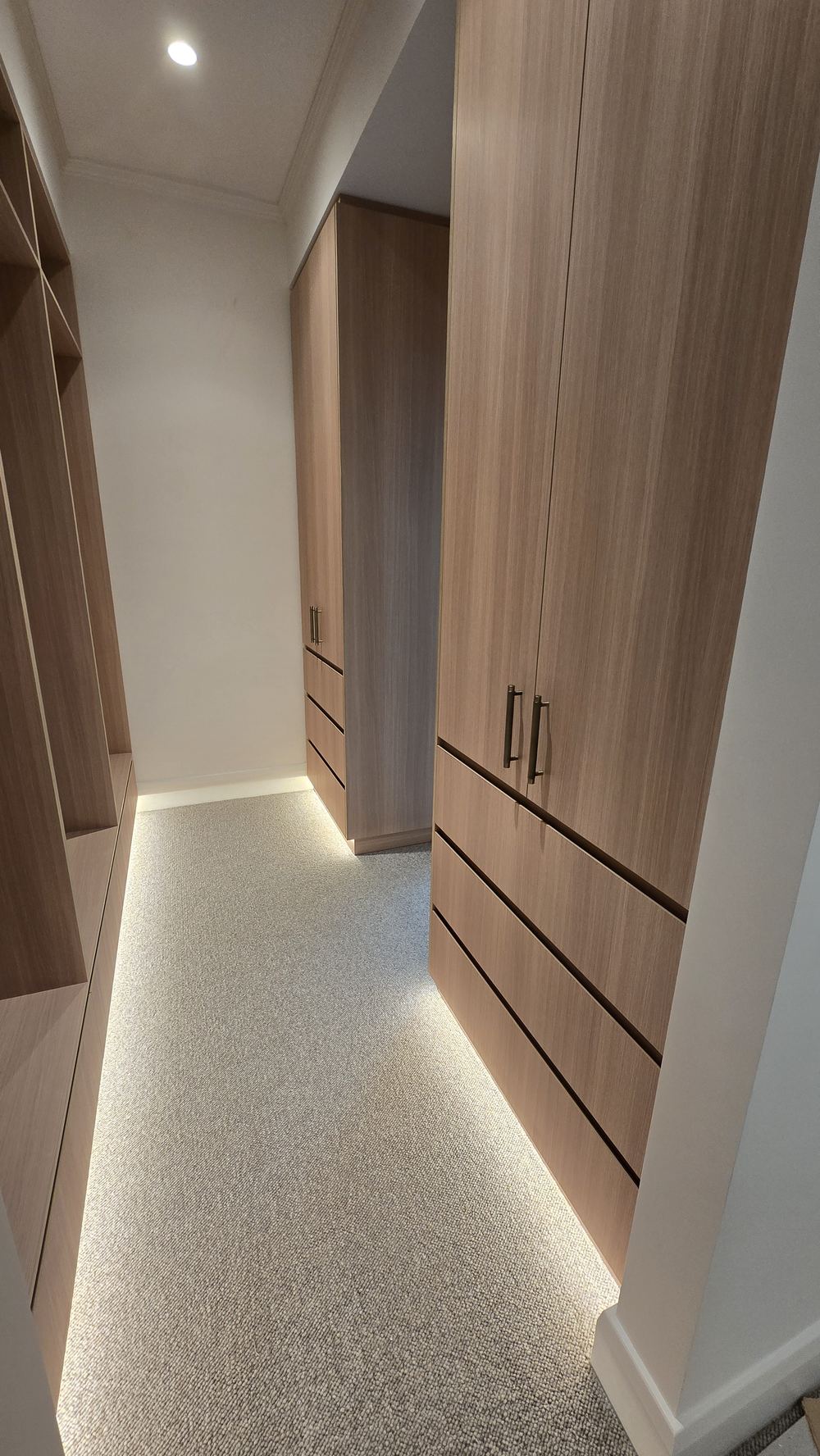Timber-lined walk-in wardrobe with LED strip lighting