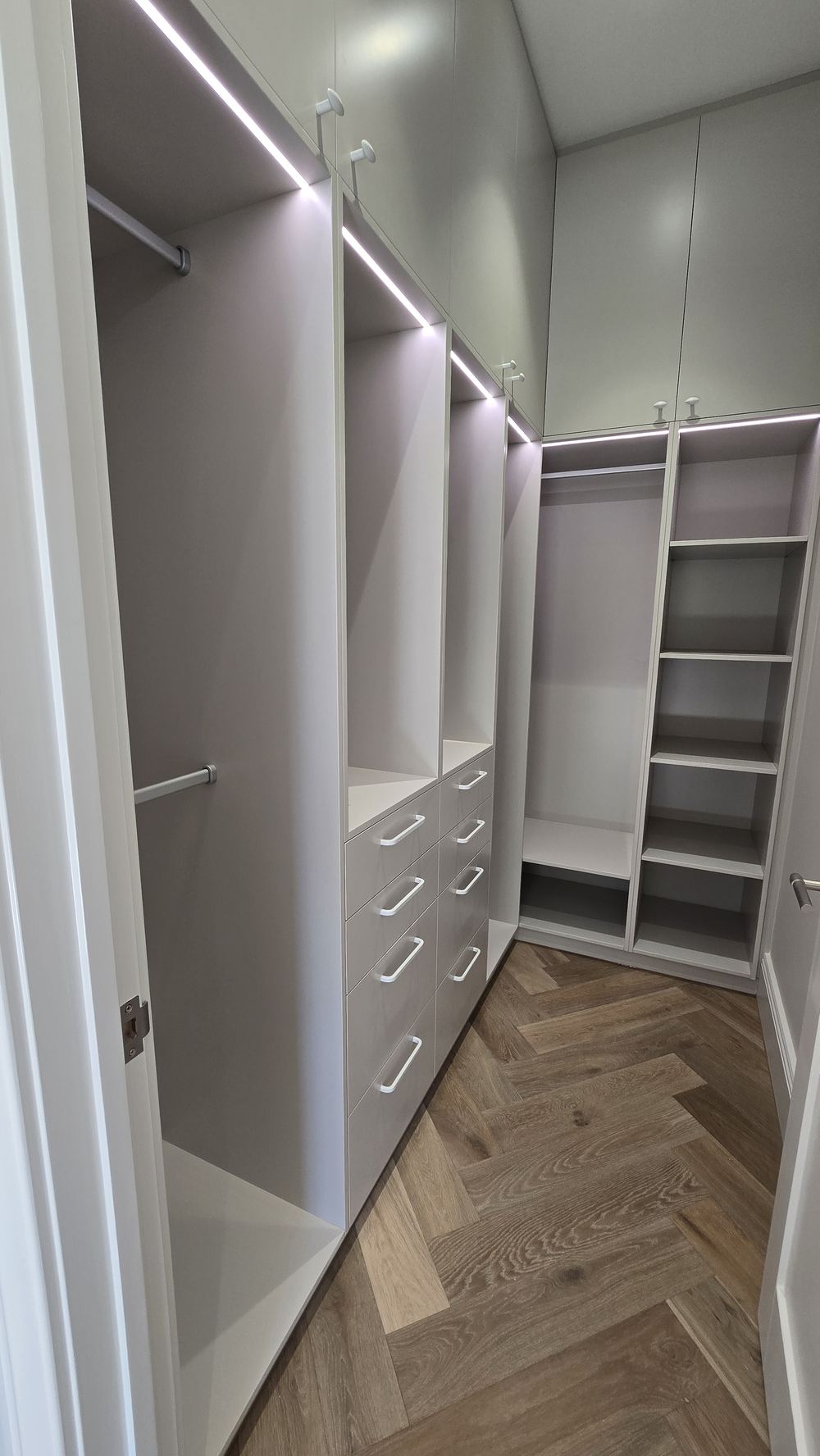 White walk-in wardrobe shelving over herringbone timber floors