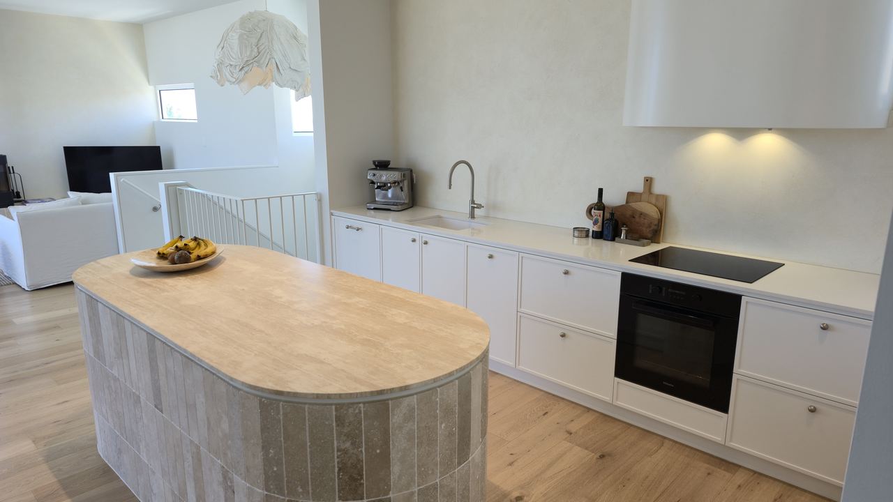 Bright open-plan custom kitchen with a travertine island bench and white cabinetry in an Adelaide home