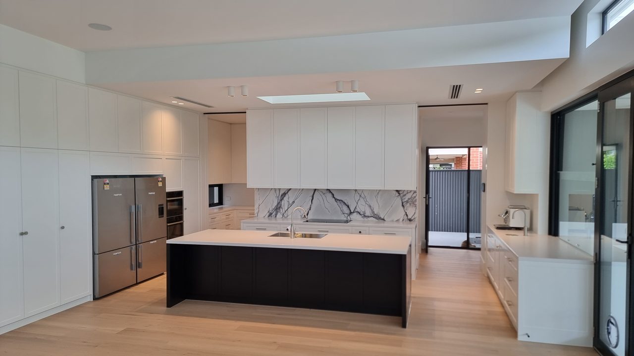 White custom kitchen with a black island bench, white stone benchtops, a marble splashback, and timber floors
