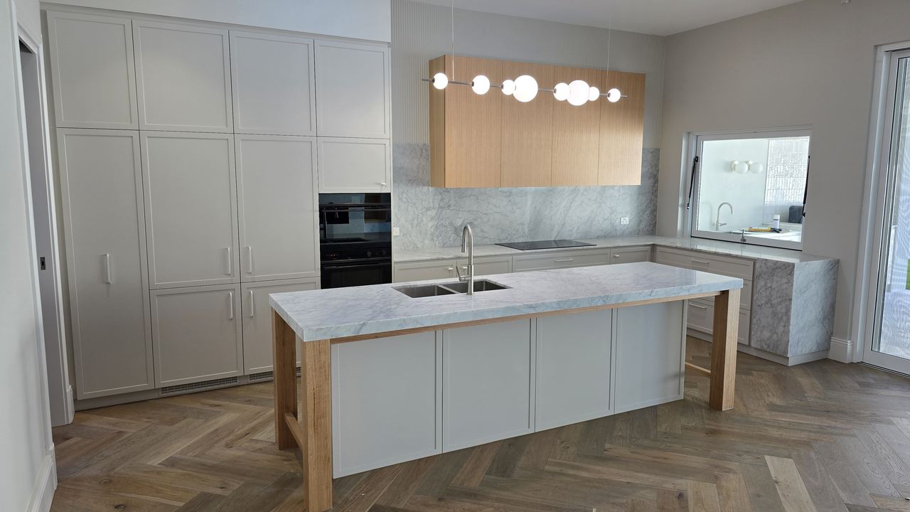 White kitchen island with timber accents and pendant lighting in an Adelaide home