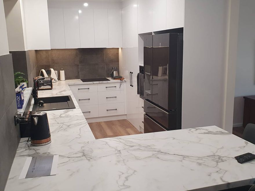 Open-plan kitchen with marble island bench and pendant lighting