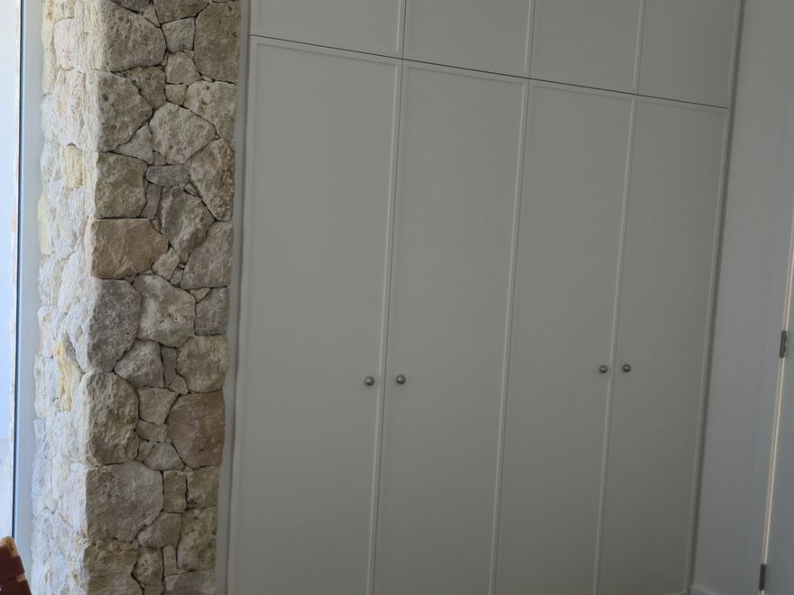 Attic bedroom with custom window seat and built-in storage against a stone feature wall