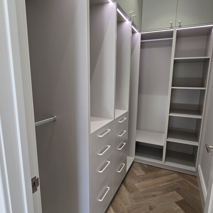 White walk-in wardrobe shelving over herringbone timber floors