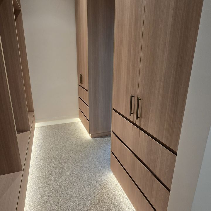 Timber-lined walk-in wardrobe with LED strip lighting